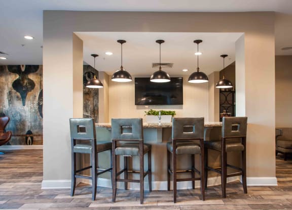 a bar with stools and a tv in a room with couches and chairs