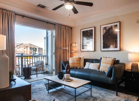a living room with a leather couch and coffee table and a sliding glass door leading to a