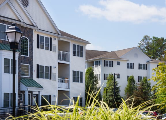 a group of white apartment buildings with grass in the foreground
