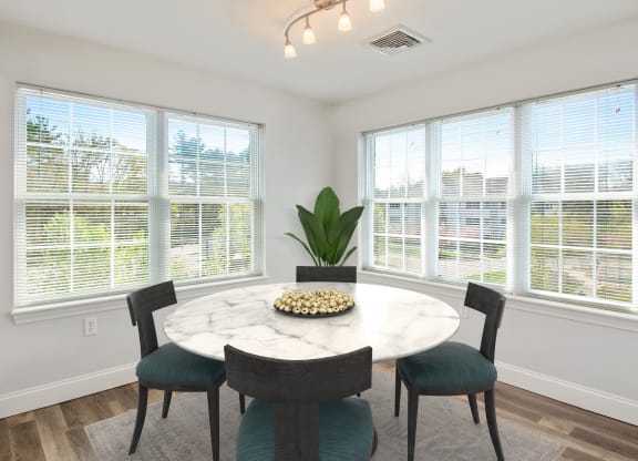 a dining room with large windows and a marble table and chairs
