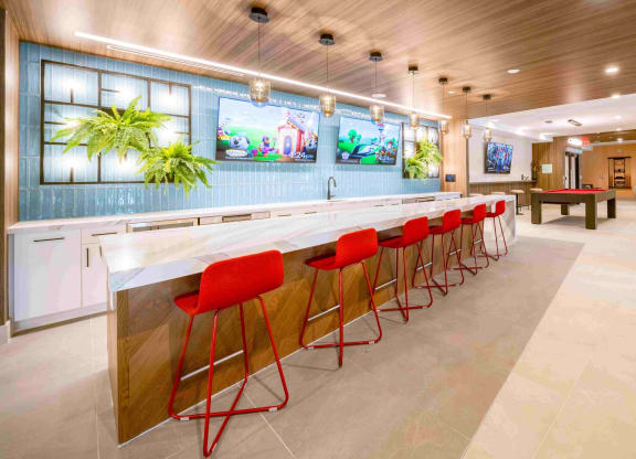 a bar with red chairs and a pool table in a lobby