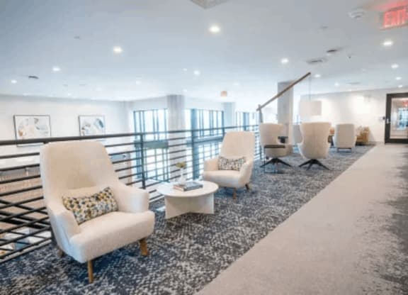 a lounge area with chairs and tables on a balcony