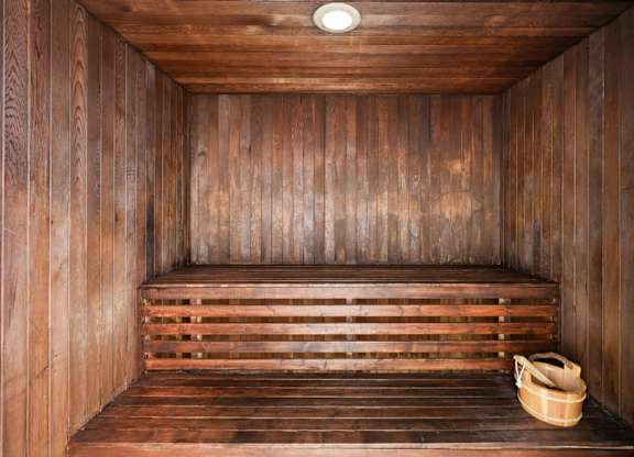 Wood-paneled community sauna with bench seating and warm lighting.