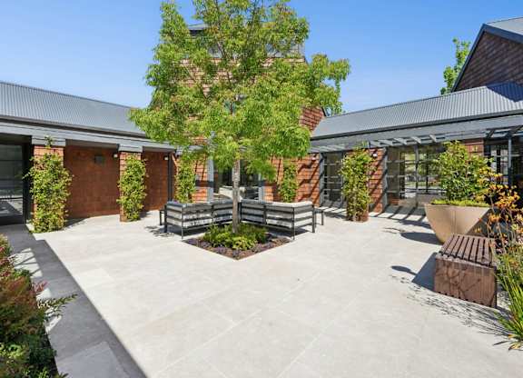 Outdoor courtyard seating area with landscaping and community pathways.
