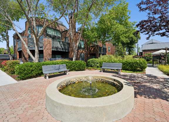 Courtyard fountain with benches, mature trees, and landscaped pathways.