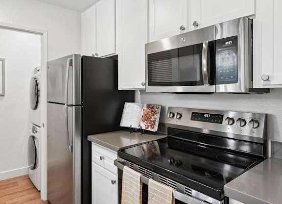 Kitchen with stainless steel appliances, white cabinetry, and in-home laundry nearby.