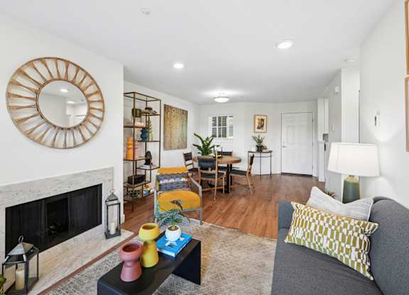Open living and dining area with fireplace, seating, and wood-style flooring.