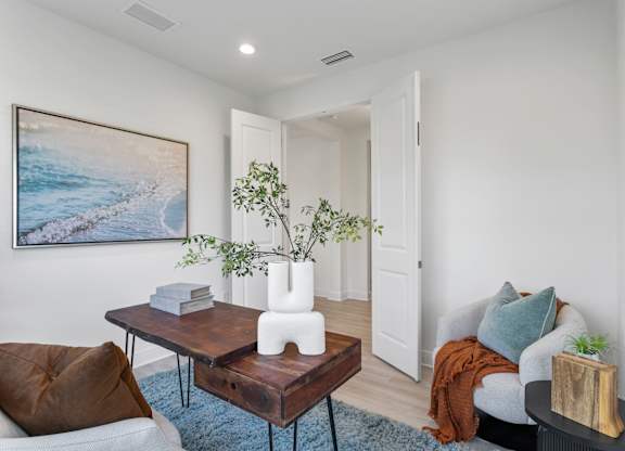 A living room with a brown chair, a coffee table, a couch, and a painting on the wall at Marisol in Lakewood Ranch, FL