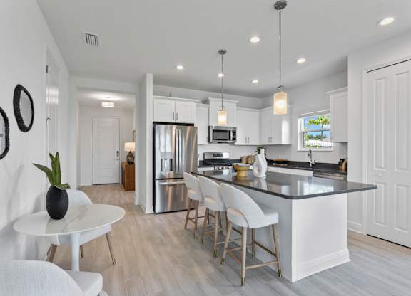 A modern kitchen with a white island and bar stools at Marisol in Lakewood Ranch, FL