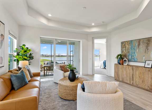 A living room with a tan couch, a white chair, and a wooden cabinet at Marisol in Lakewood Ranch, FL