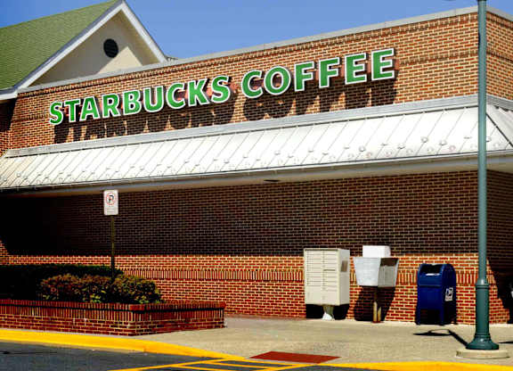 A Starbucks Coffee sign on a brick building.