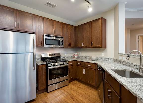 A kitchen with wooden cabinets and a stainless steel refrigerator.