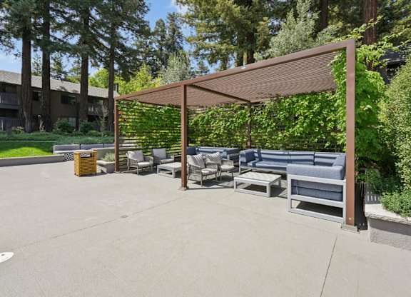 Poolside cabana with seating and nearby swimming pool at Old Orchard Apartments