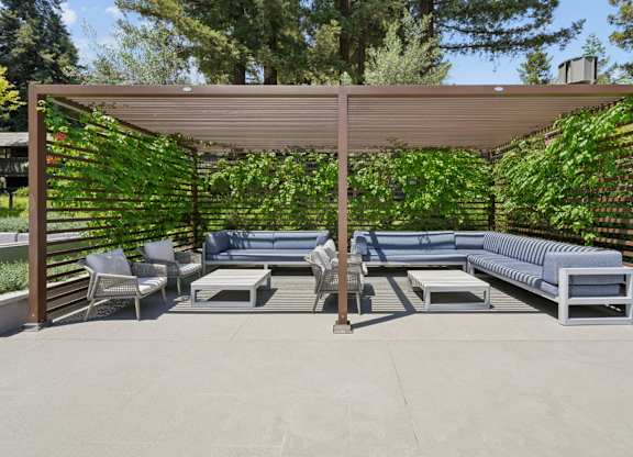 Covered outdoor cabana with seating and lounge furniture at Old Orchard Apartments