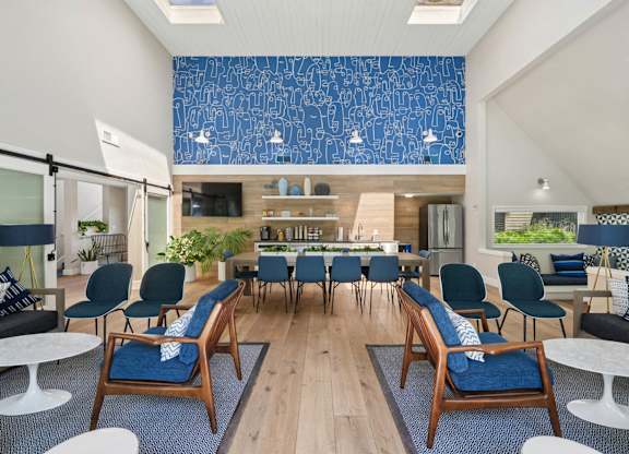 Clubhouse interior with dining table, lounge seating, and large windows with outdoor views