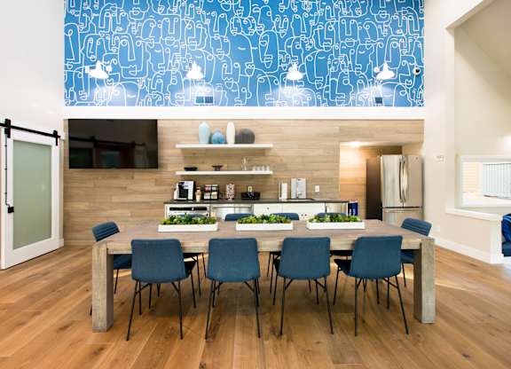 Clubhouse kitchen with stainless steel appliances, blue accent wall, and large communal dining table