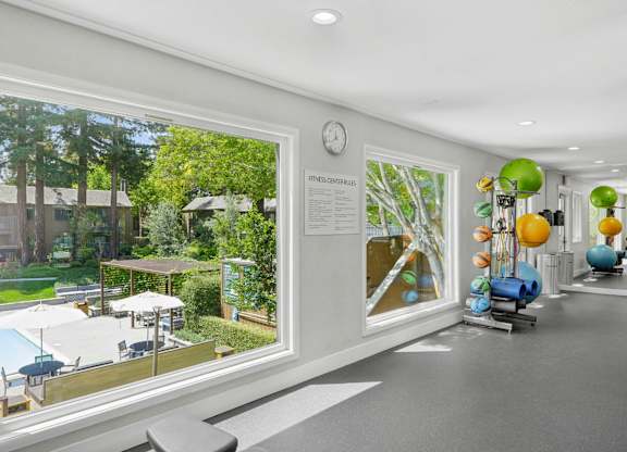 Fitness room with free weights, bench, and large window overlooking greenery at Old Orchard
