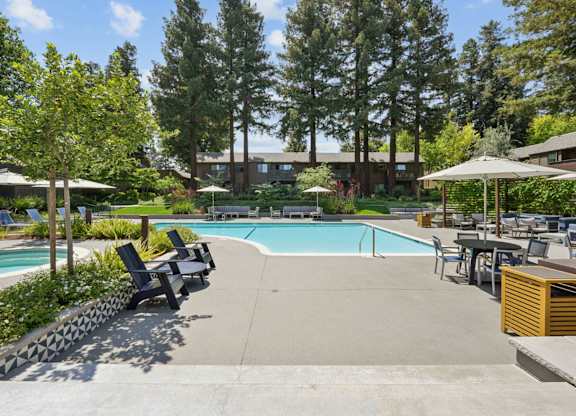 Pool area with seating and greenery at Old Orchard Apartments