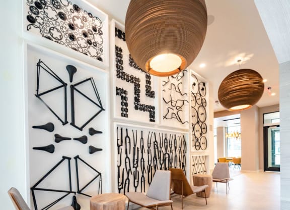 the lobby of a hotel with chairs and a wall filled with art