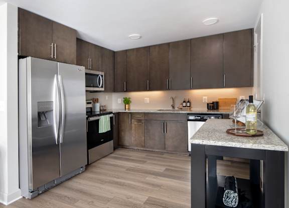 A modern kitchen with a stainless steel refrigerator and wooden cabinets.