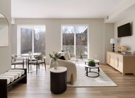 A modern living room with a white sofa, a white armchair, a white coffee table, and a white side table.
