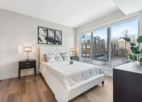 a bedroom with a large window and a white bed