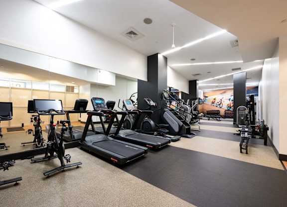 a gym with cardio equipment and weights on the floor