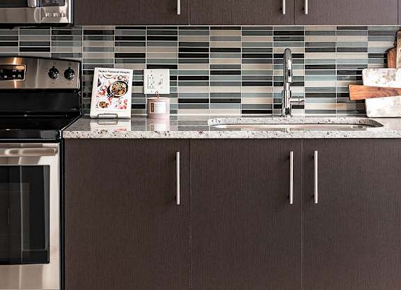 A kitchen with brown cabinets and a stainless steel oven.
