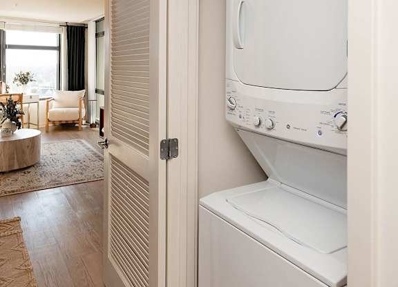 A white dryer is sitting in a room with a round table and chairs.