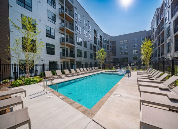an outdoor pool with lounge chairs and an apartment building