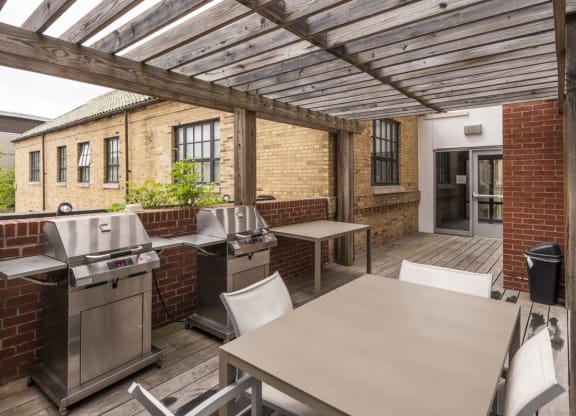 a patio with a barbecue grill and a table with chairs