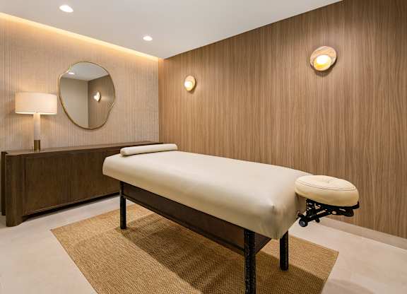 Private massage room with a padded treatment table, soft lighting, and neutral finishes in the Parc Huron spa.