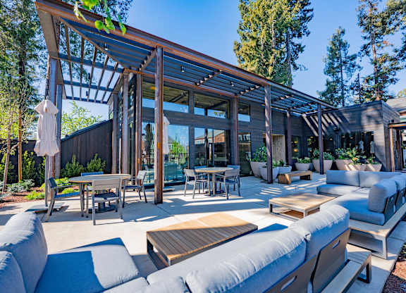 A modern outdoor living space with a wooden pergola and comfortable seating.