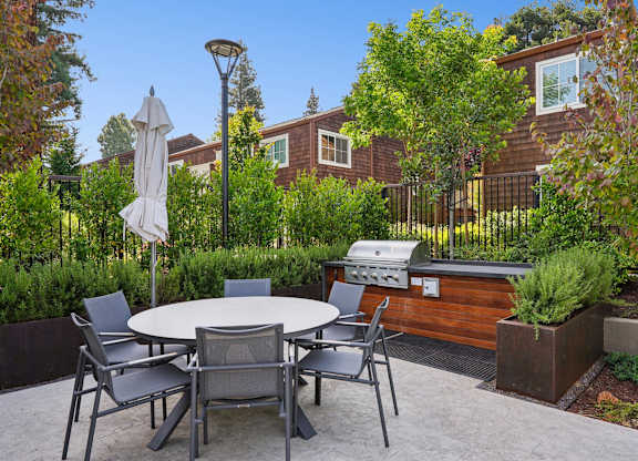 A patio with a table and chairs and a grill.