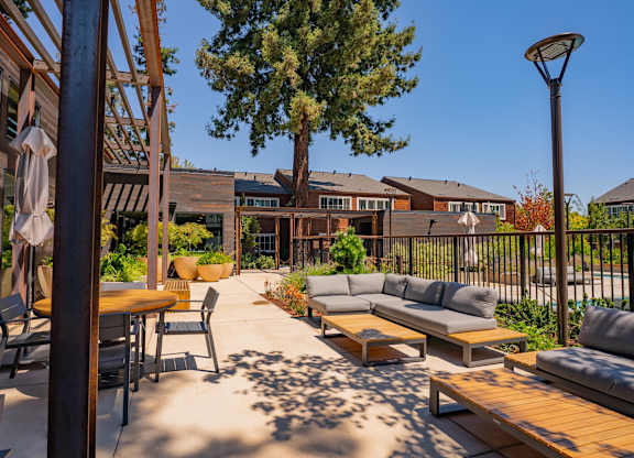A patio with a table, chairs, and a tree.