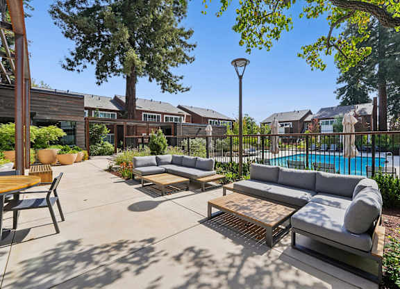 A sunny day at a poolside patio with a table and chairs.