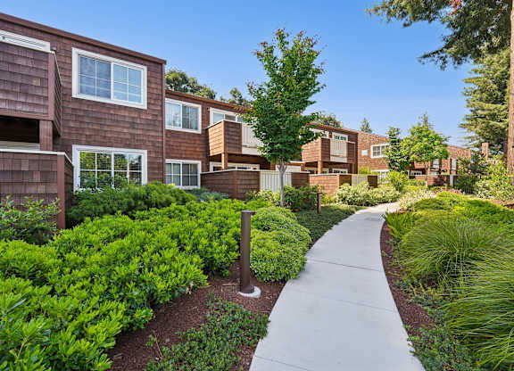 A walkway leads through a landscaped area in front of apartment buildings.
