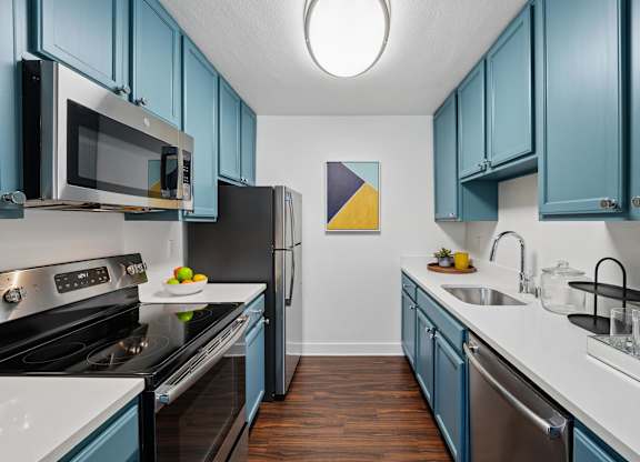A kitchen with blue cabinets and stainless steel appliances.