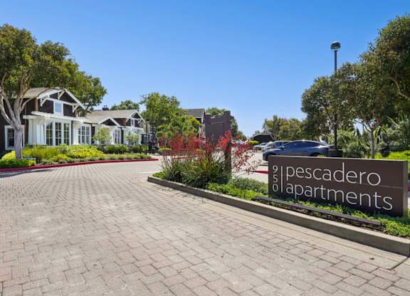 Entrance sign and landscaped drive at Pescadero Apartments community.