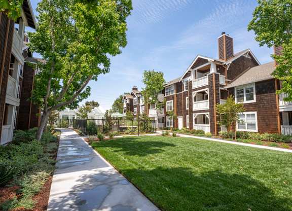 Landscaped courtyard at Pescadero Apartments with open lawn, walking paths, and garden-style surroundings.