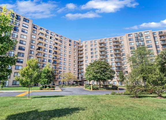 a view of a large apartment complex with grass and trees