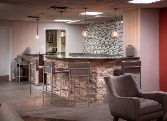 a lobby with chairs and a bar with a stone wall