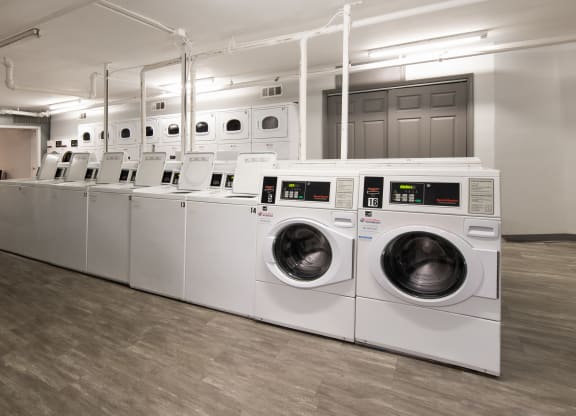 a row of white washers and dryers in a laundry room