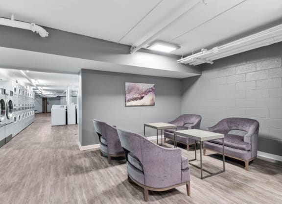 a laundry room with purple chairs and tables and a washing machine