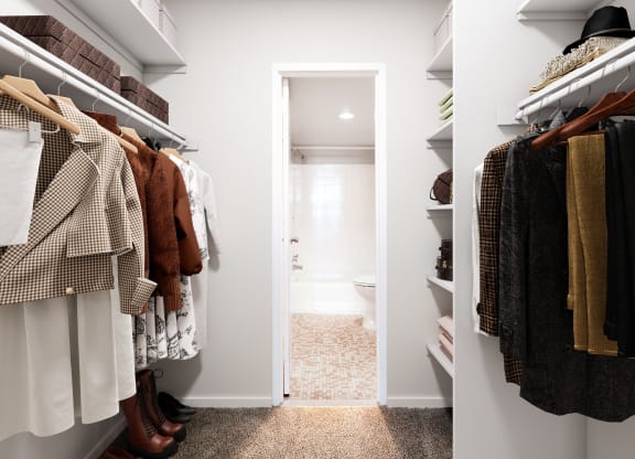 a walk in closet filled with clothes and a door to a bathroom