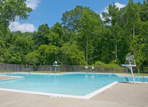 a swimming pool with a fence around it and trees in the background
