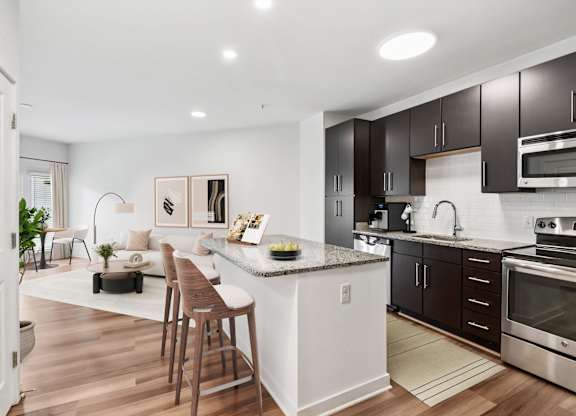 A modern kitchen with dark brown cabinets and stainless steel appliances.