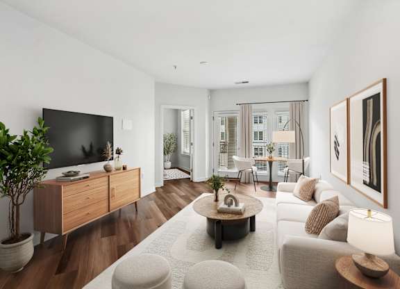 A modern living room with a flat screen TV, a coffee table, and a large window.