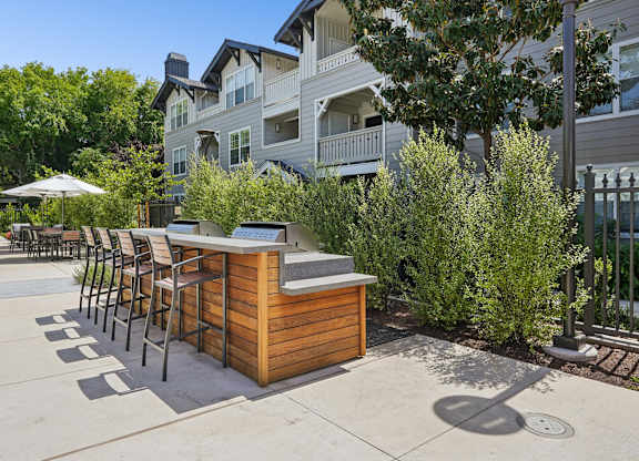 Outdoor grilling station with seating near indoor pool building at The Presidio Apartments