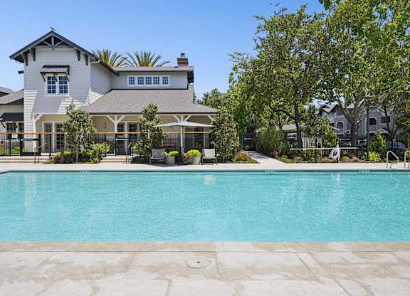 Outdoor pool with surrounding deck, seating, and landscaped areas